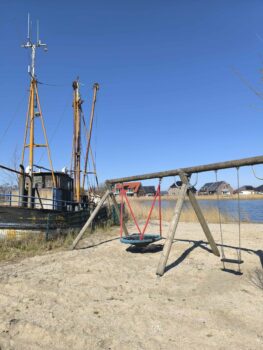Spielplatz mit altem Boot im Hintergrund