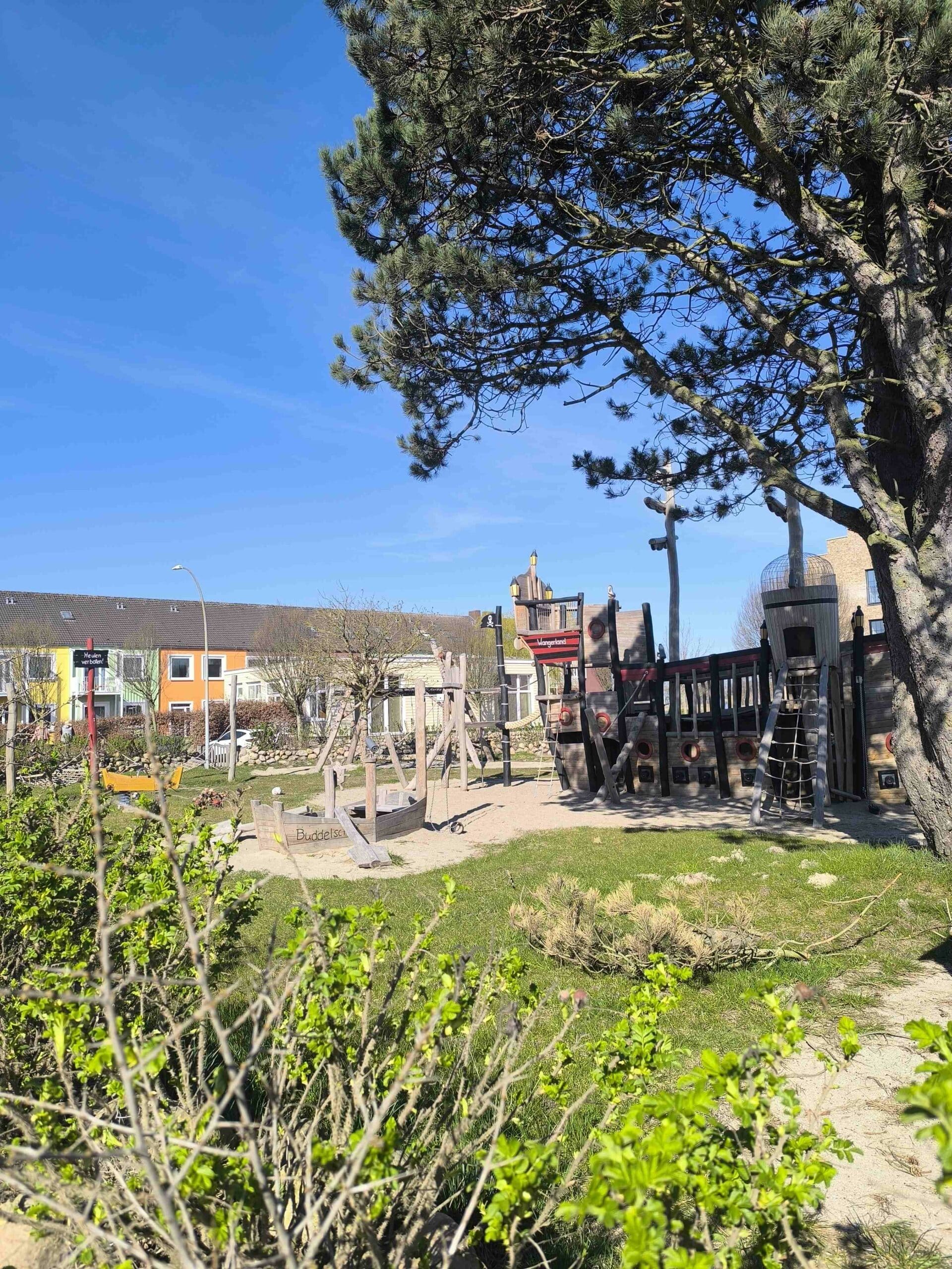 Spielplatz im Grünen mit Blick auf Wohngebäude im Wangerland Resort