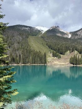 Klarer blauer See mit schneebedeckten Bergen im Hintergrund