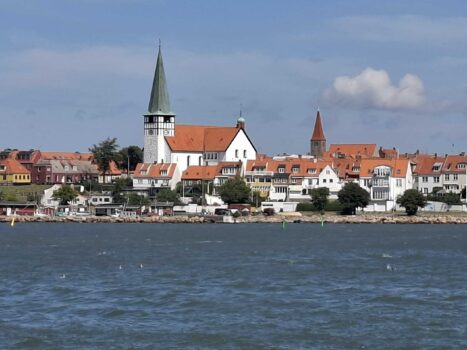 Kleines Dorf mit Kirchturm zieht vom Wasser aus vorbei