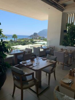 Sitzplätze des Restaurants mit Blick auf den Hotelgarten und das Meer